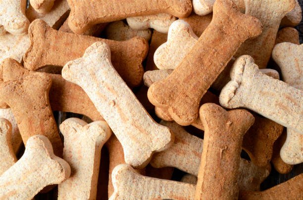 A close up image of several dog treats on a old wooden table top.